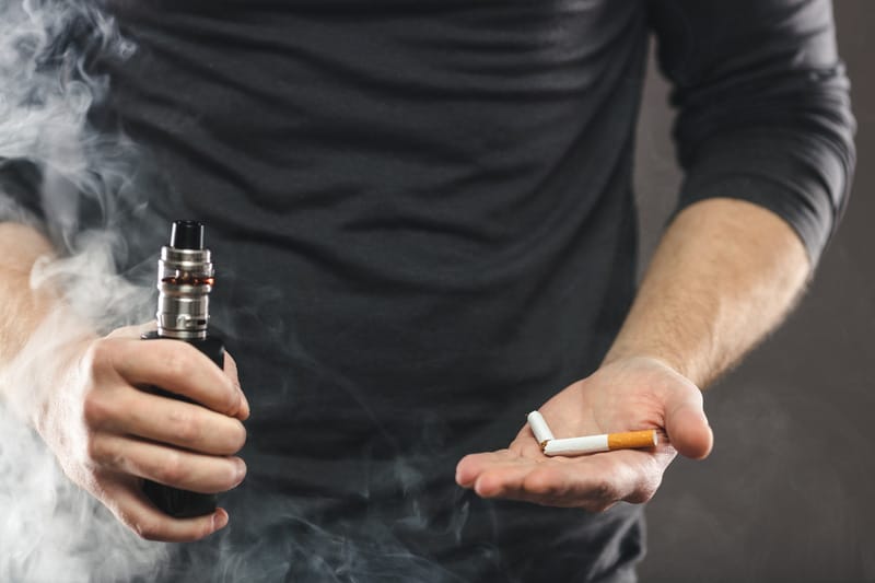 Person vaping an e-cigarette, a source of nicotine that shows up on cotinine tests