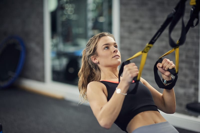 Woman doing pull-ups to strengthen her back muscles while losing back fat