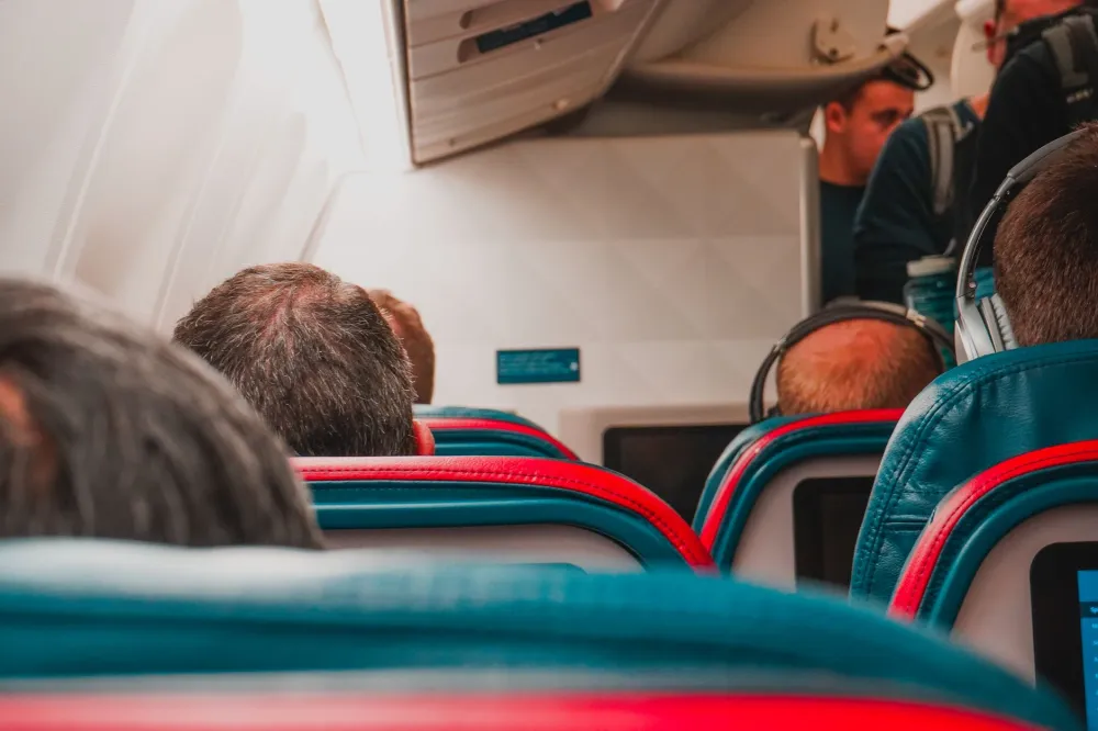 Woman yawning in airplane seat to relieve blocked ear pressure during flight