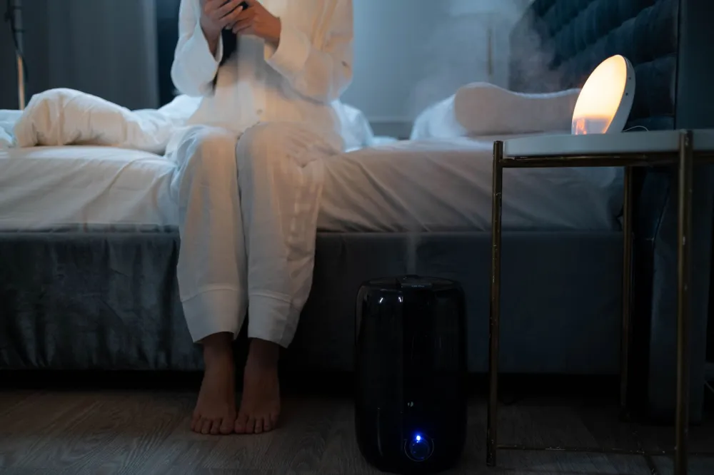 Small humidifier running on a bedroom nightstand next to a glass of water at night