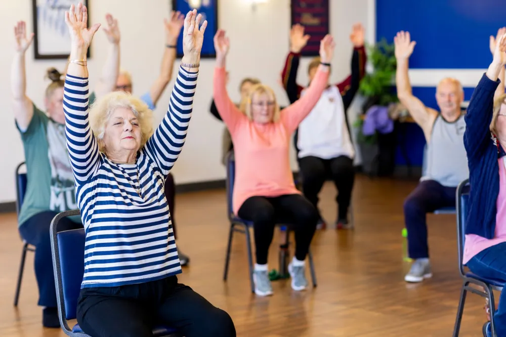 Group of adults over 40 practicing yoga poses in a bright studio
