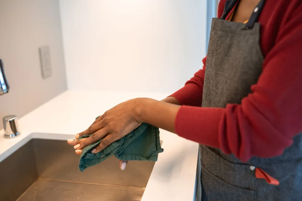 Person thoroughly washing hands at kitchen sink to prevent seasonal illness spread