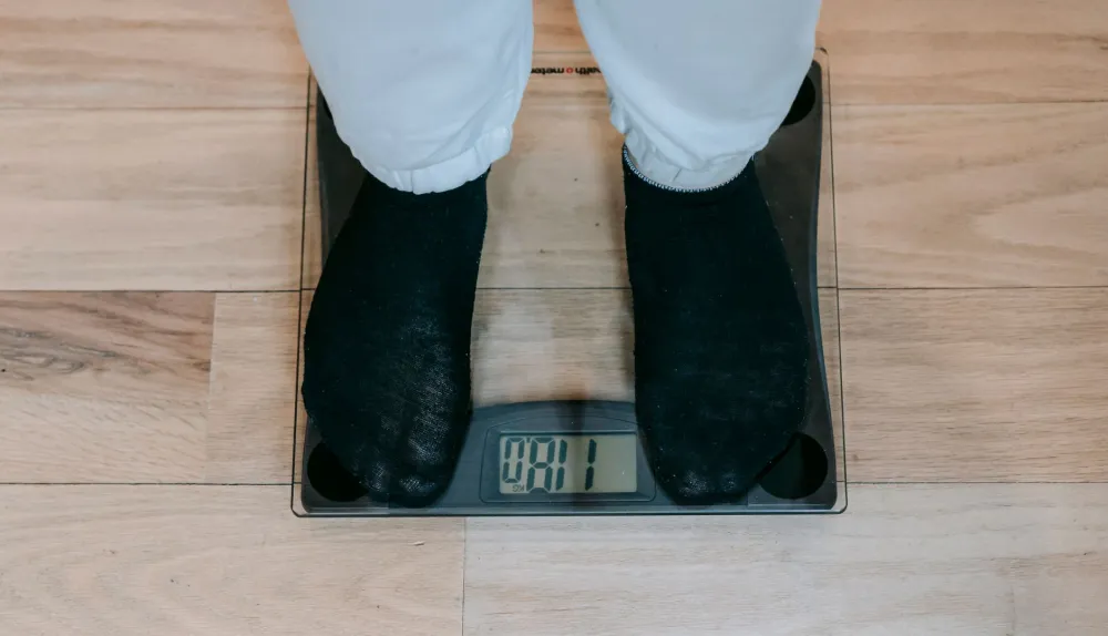 Person stepping on bathroom scale tracking keto diet weight loss progress