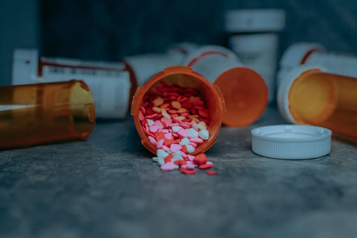 Person holding prescription bottle next to dollar bills, GLP-1 drug cost concept