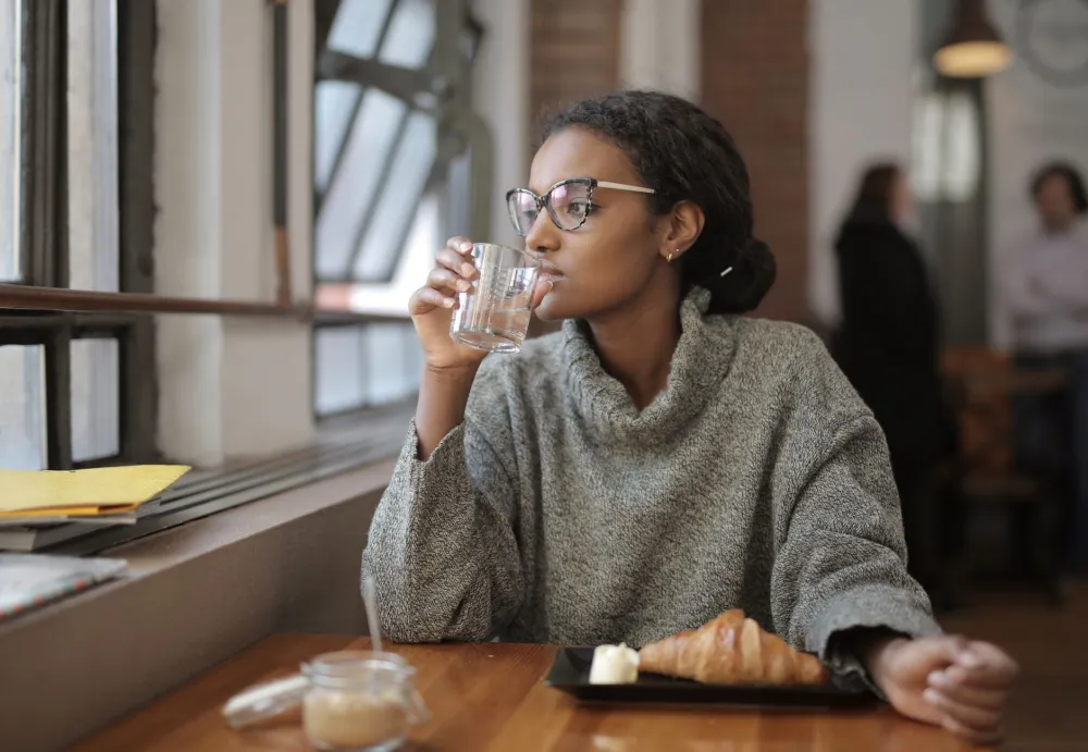 Woman drinking a glass of water in the morning during an intermittent fasting routine