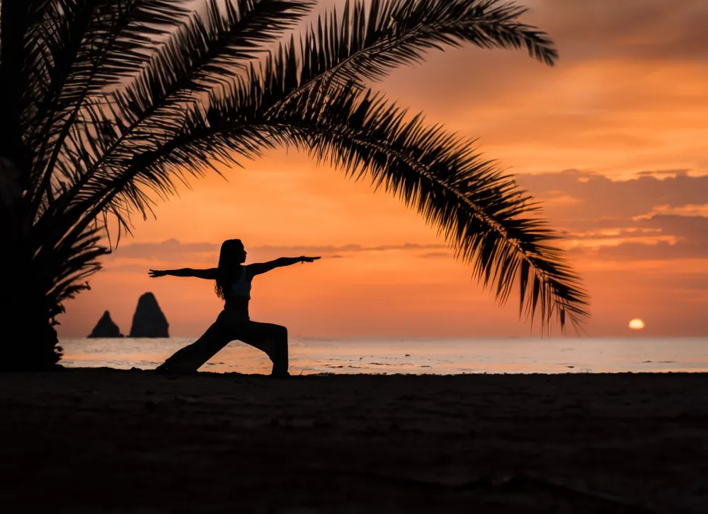Woman holding warrior yoga pose indoors as part of a cancer-prevention movement routine
