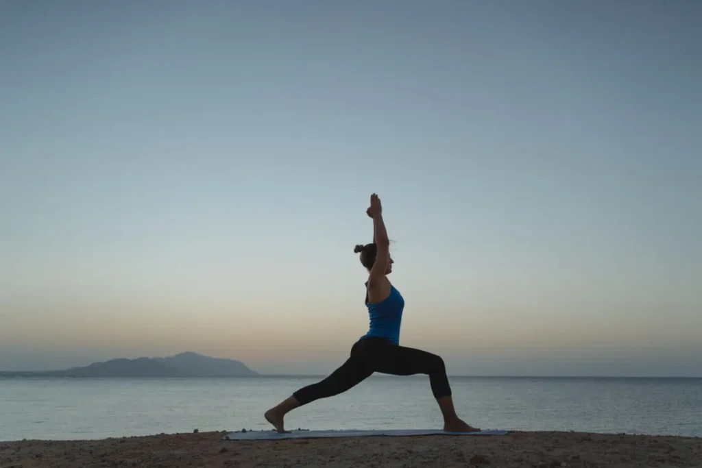 Woman practicing morning yoga routine on a mat at sunrise outdoors