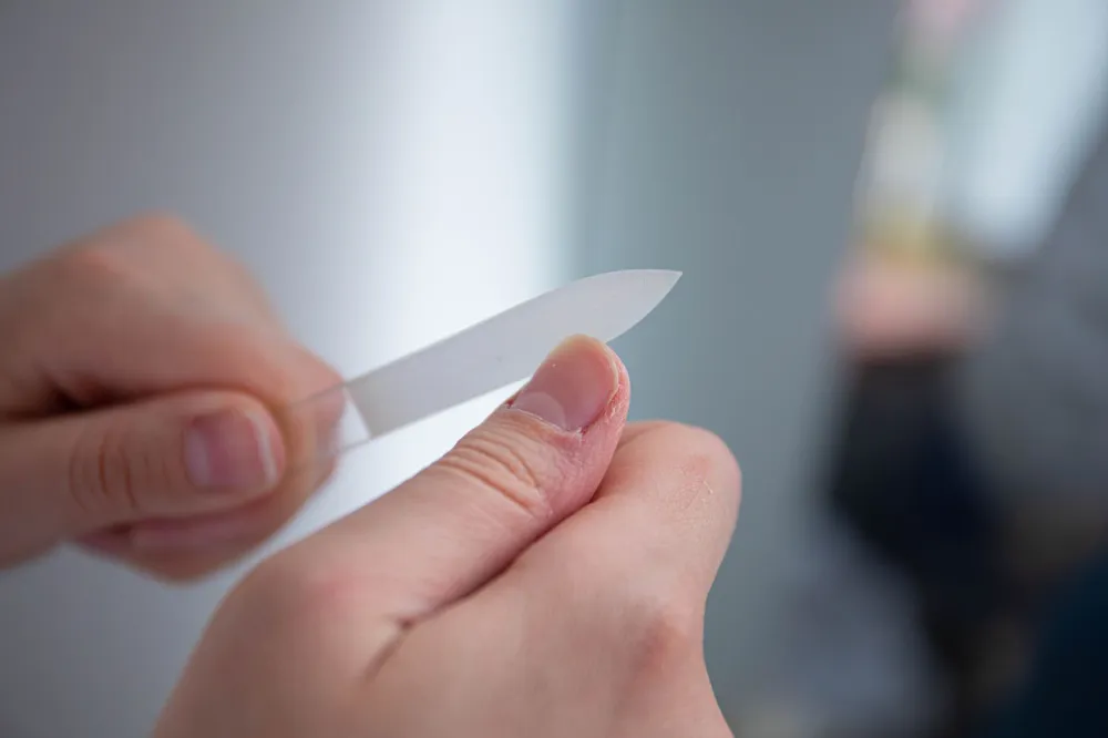 Woman carefully examining her fingernails for nail health changes and discoloration