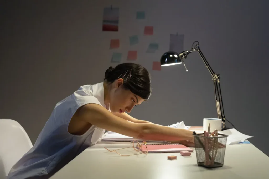 Woman performing neck stretches at office desk to relieve pain