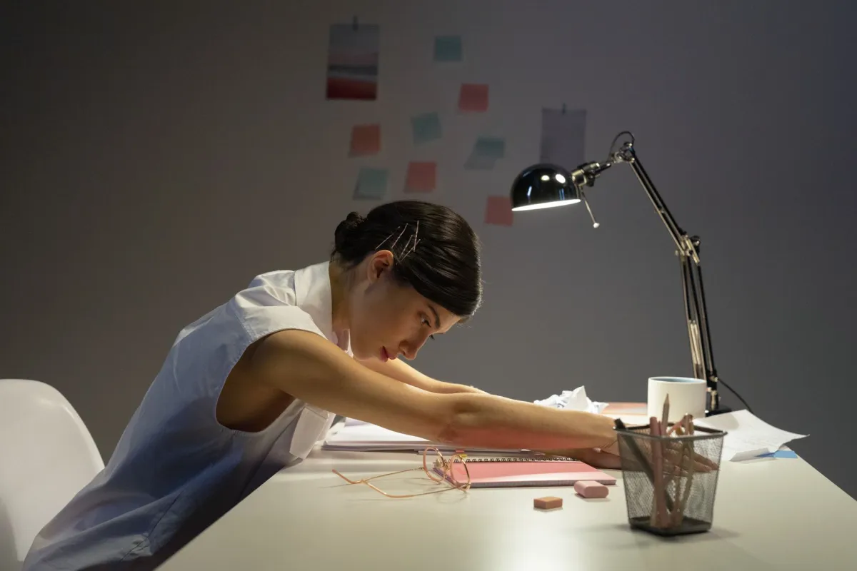 Woman performing neck stretches at office desk to relieve pain