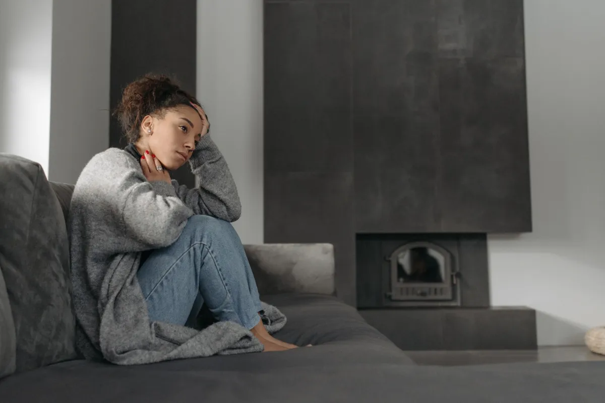 Woman touching her throat indoors experiencing post-nasal drip discomfort