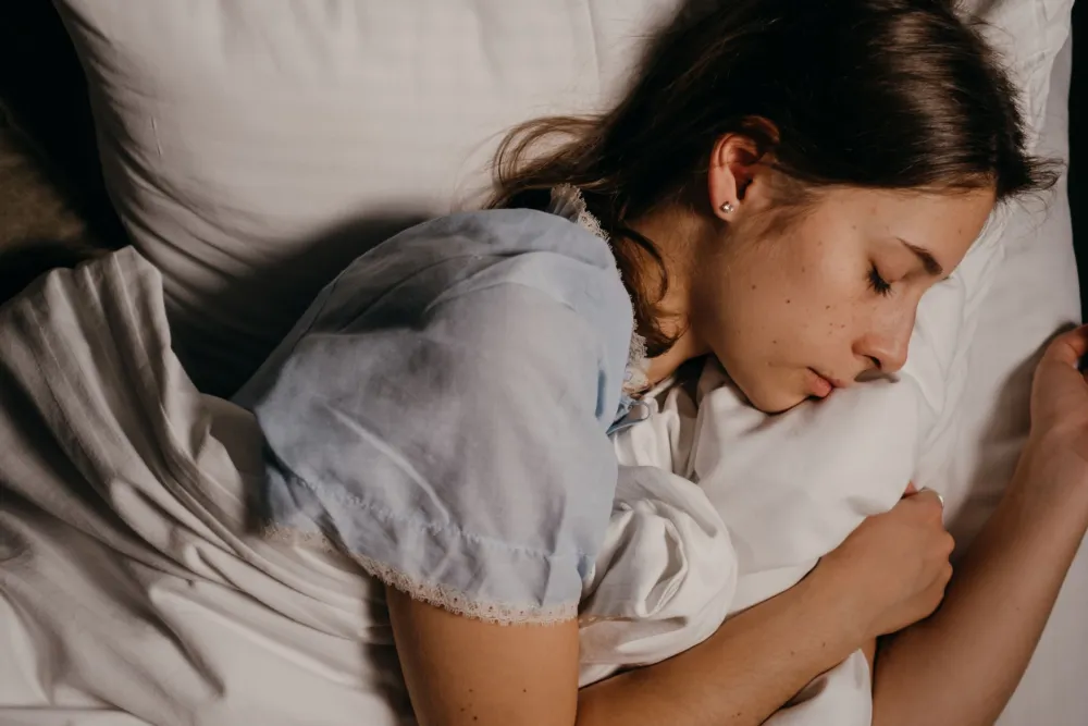 Person sleeping peacefully in dark bedroom showing restorative sleep for longevity