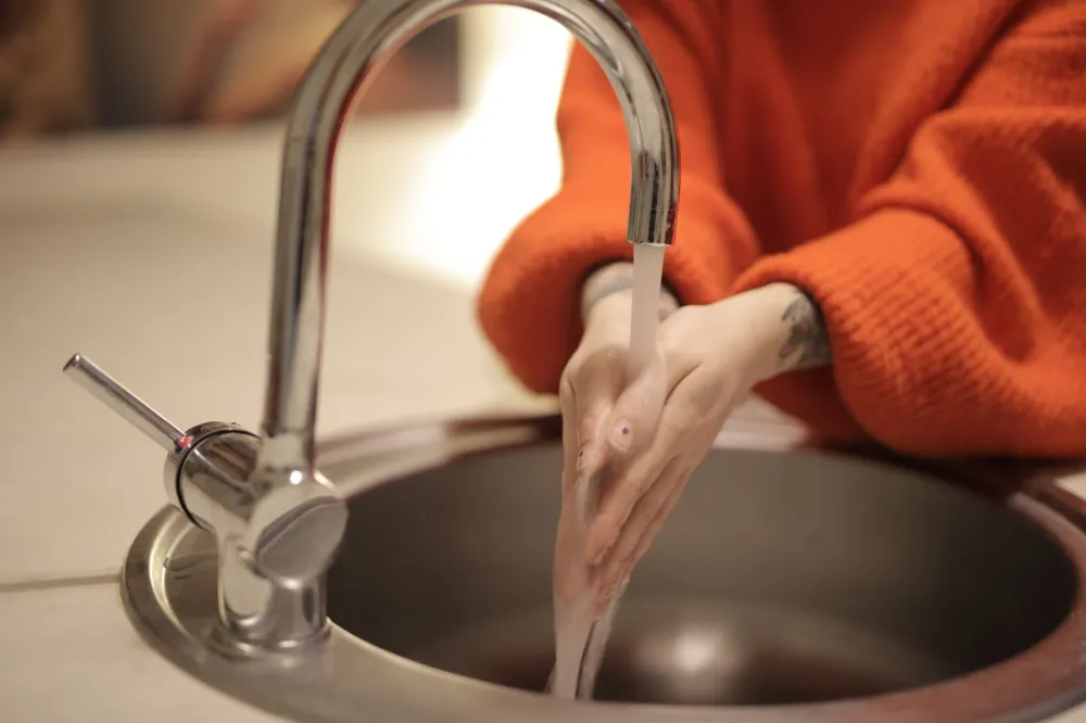 Person thoroughly washing hands at sink to prevent stomach bug spread