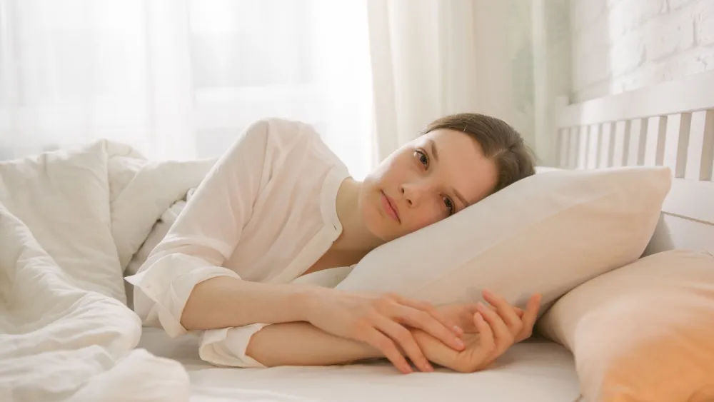 Woman resting in a bright bedroom during safe recovery from a stomach illness