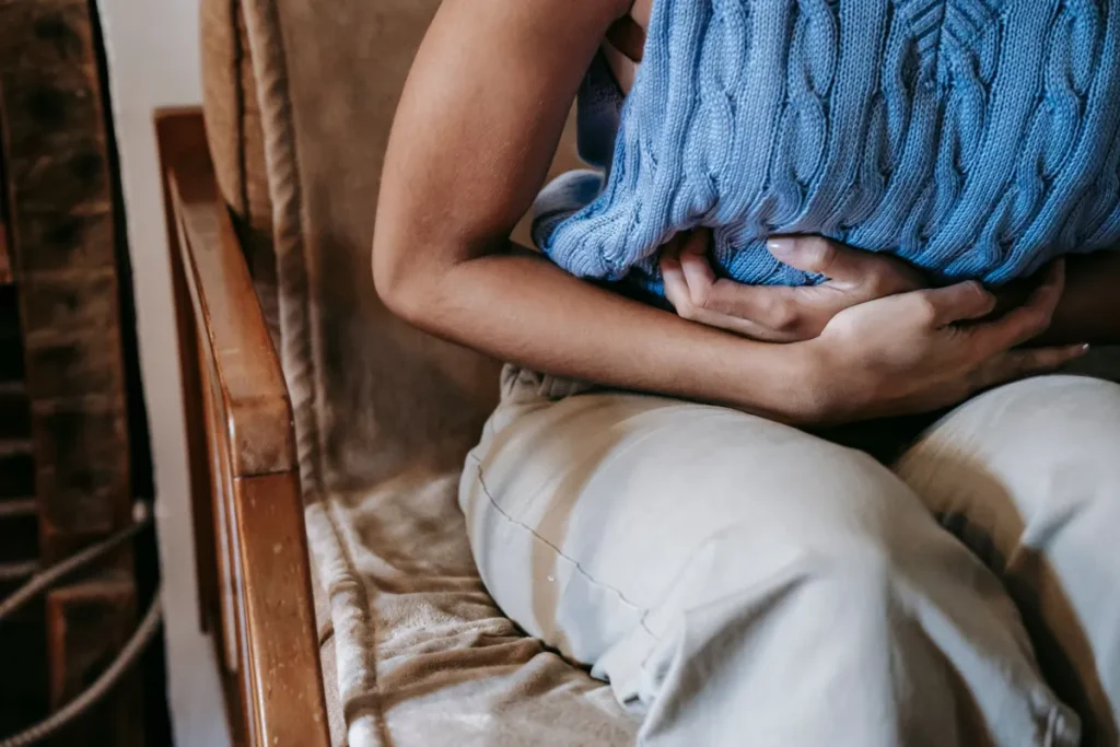 Woman holding her stomach showing stress and gut health discomfort at home