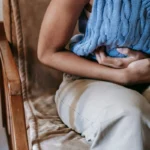Woman holding her stomach showing stress and gut health discomfort at home