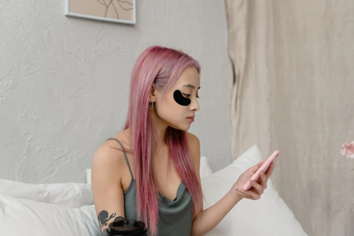 Woman applying skincare product under eyes to reduce dark circles and puffiness