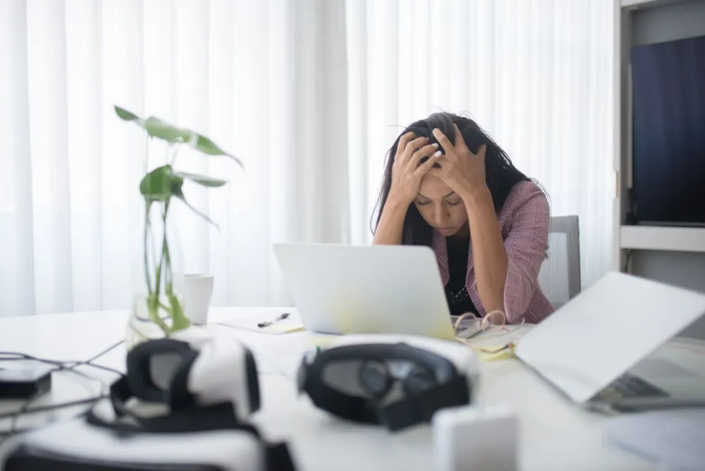Stressed adult woman working on laptop late at night triggering skin flare-ups
