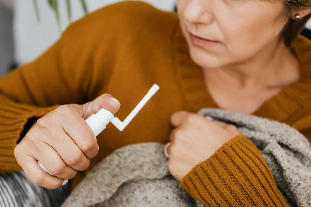 Hand holding a saline nasal spray used to prevent blocked ears on airplane flights