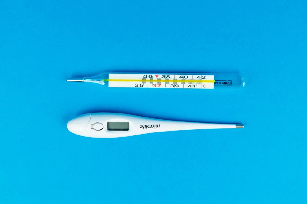 Close-up of a thermometer showing fever temperature during flu or COVID illness