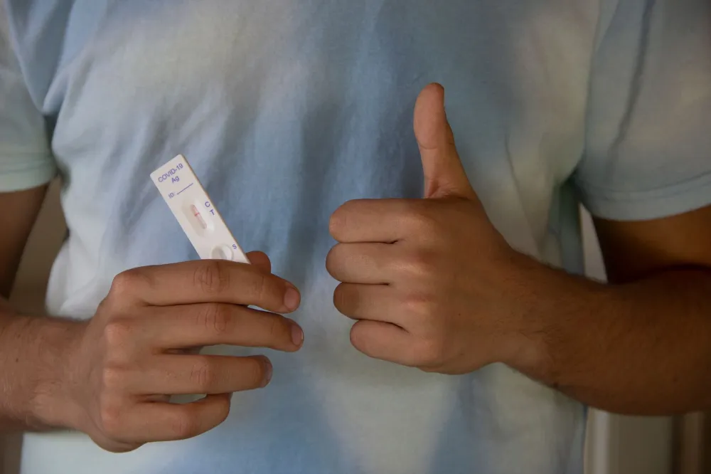 Woman reading a COVID-19 rapid antigen home test on a kitchen counter