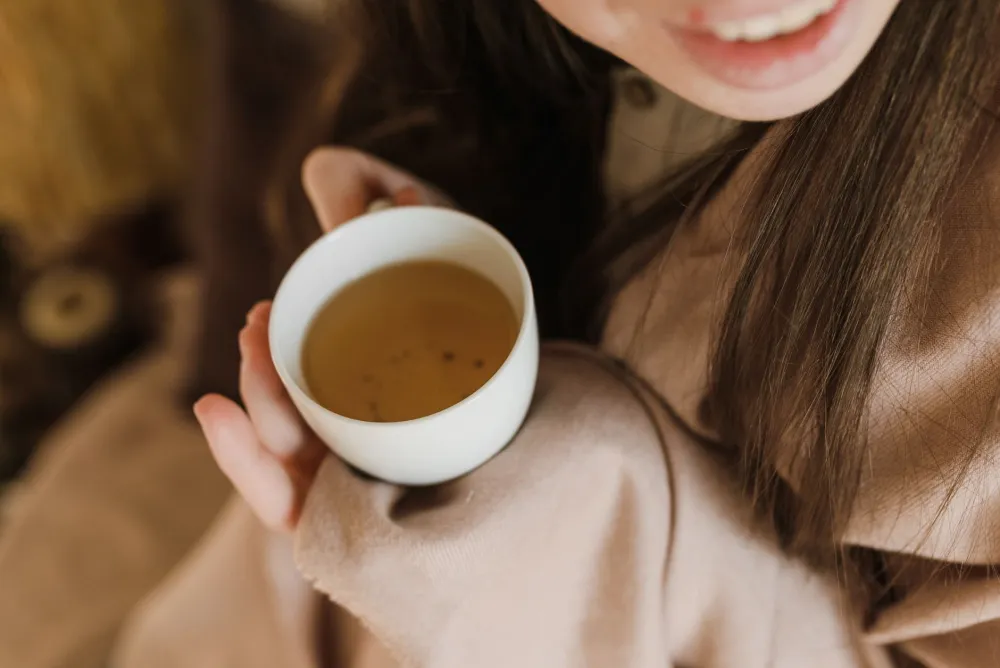 Sick person resting on couch drinking hot tea during respiratory illness recovery