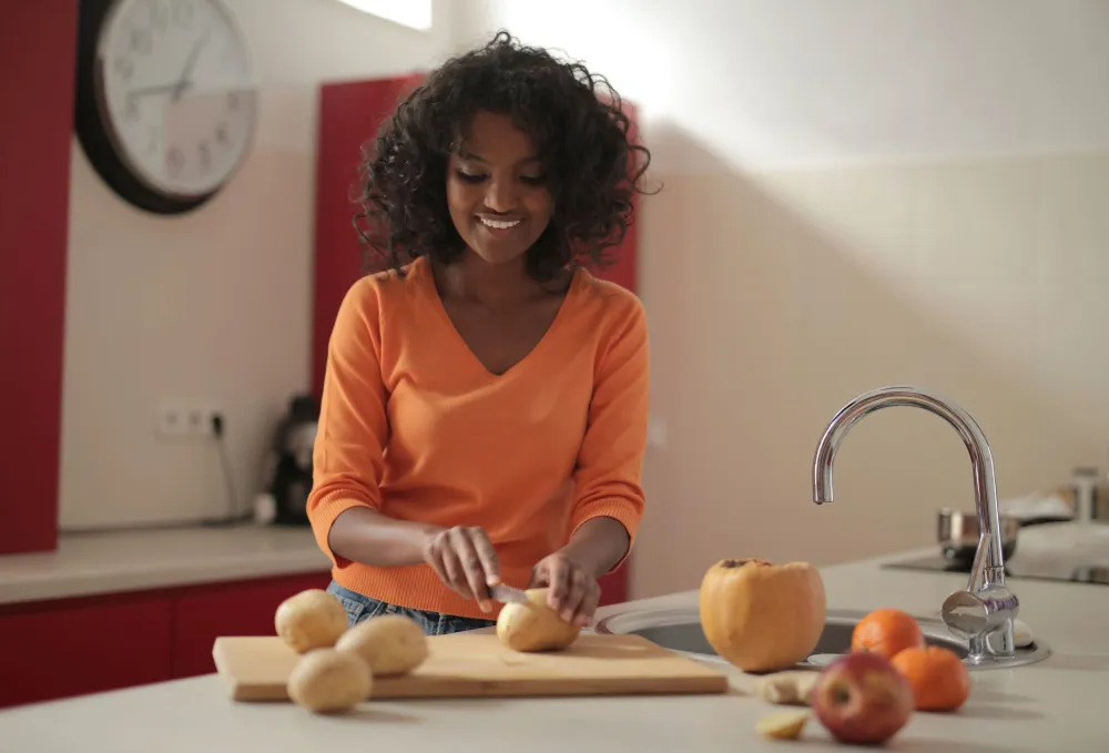 Woman chopping fresh vegetables for weekly meal prep on a wooden cutting board