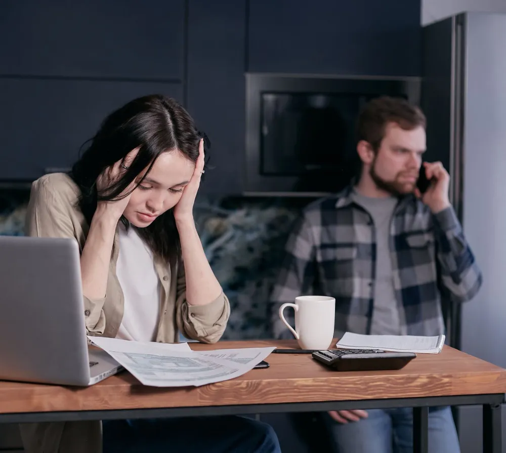 Woman looking stressed while sorting through healthcare paperwork at kitchen table