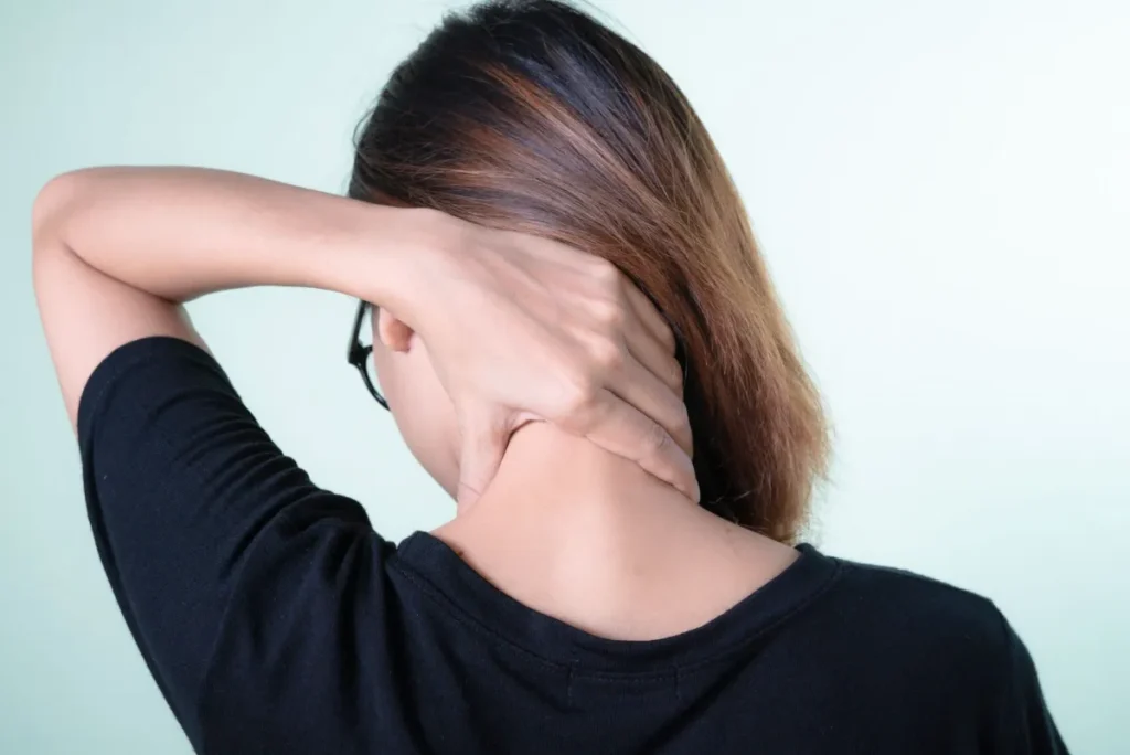 Woman holding her neck in pain after waking up, needing a better pillow for neck pain