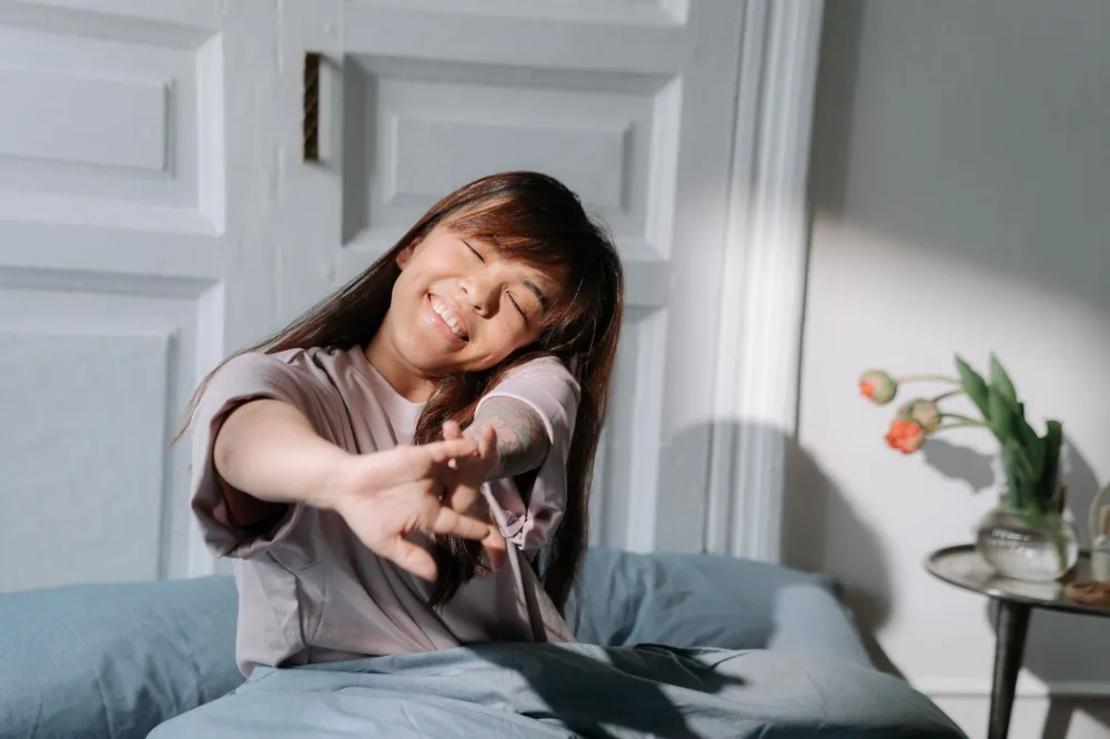 Woman stretching in bright bedroom during a consistent morning routine after restful sleep
