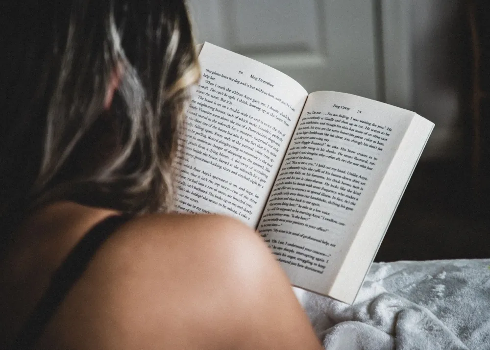 Person reading a book in bed as part of a calming pre-sleep routine for better REM sleep