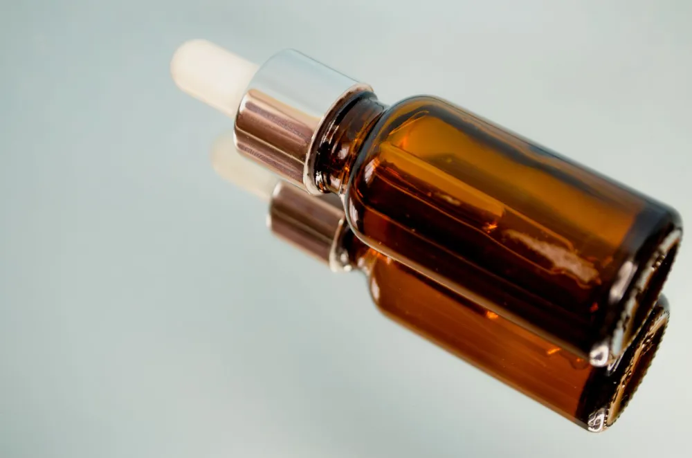 Close-up of retinol serum dropper bottle next to moisturizer on bathroom shelf