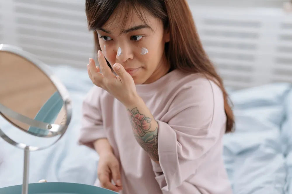 Young woman applying thick moisturizer over retinol to reduce skin irritation at night