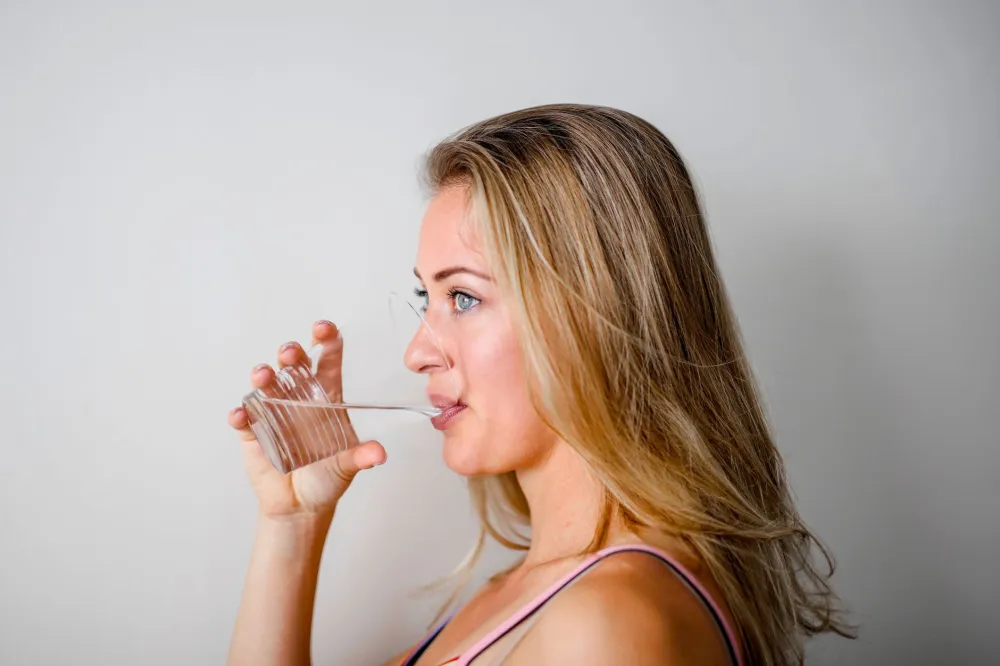 Glass of water beside a person with calm, hydrated skin after skin barrier recovery
