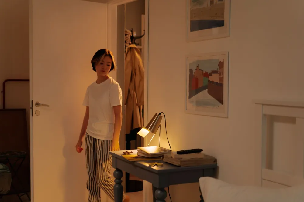 Sleep Hygiene Habits That Transform Your Nights 2 Woman dimming warm bedroom lights as part of a nightly sleep hygiene routine