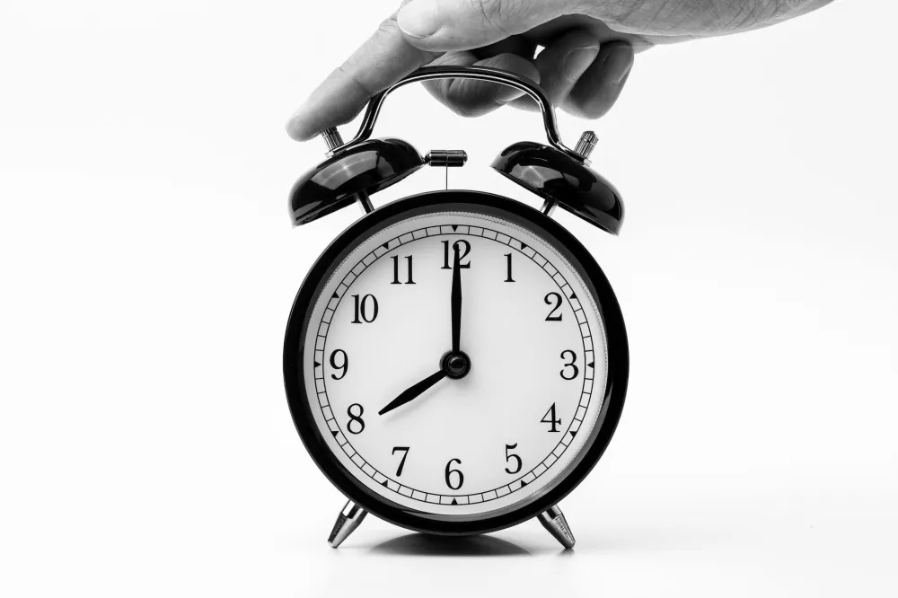 Sleep Hygiene Habits That Transform Your Nights 4 Analog alarm clock on a bedside table representing a consistent sleep schedule habit