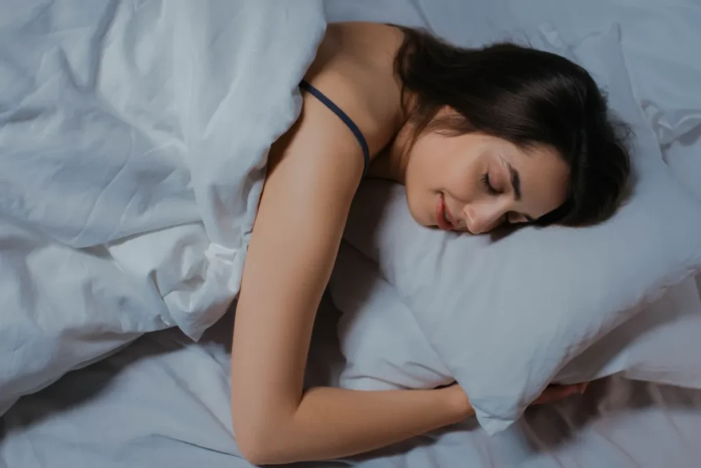 Person sleeping peacefully in a dark bedroom practicing good sleep hygiene habits