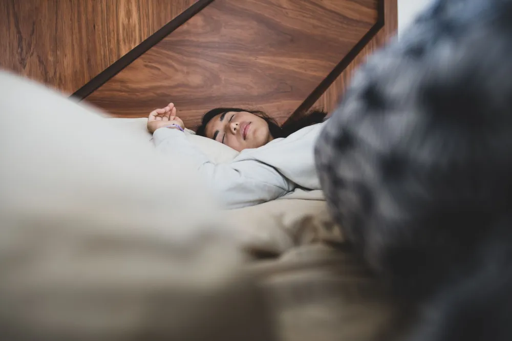 Woman sleeping peacefully in a dark bedroom, supporting healthy weight management