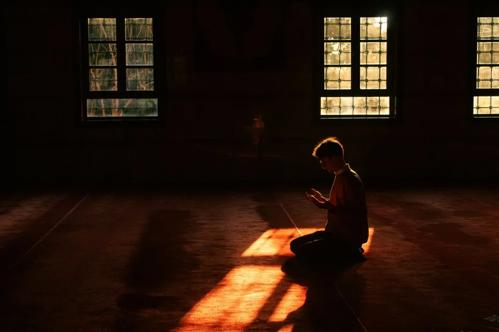 Person meditating in morning sunlight to lower cortisol and support weight loss
