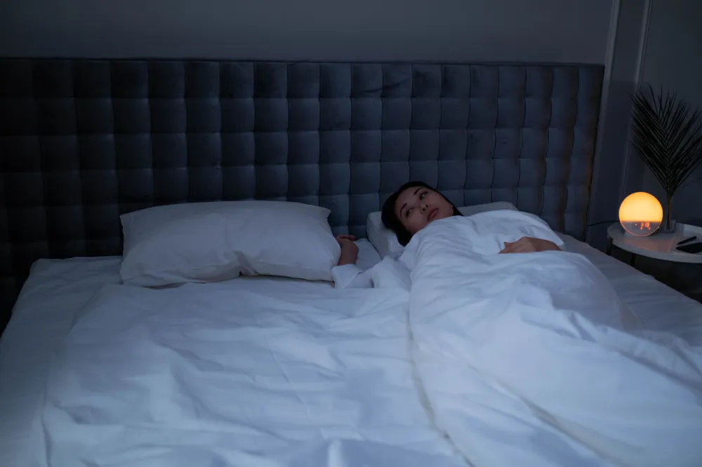 Person following a calming evening routine with dim lights to improve sleep quality