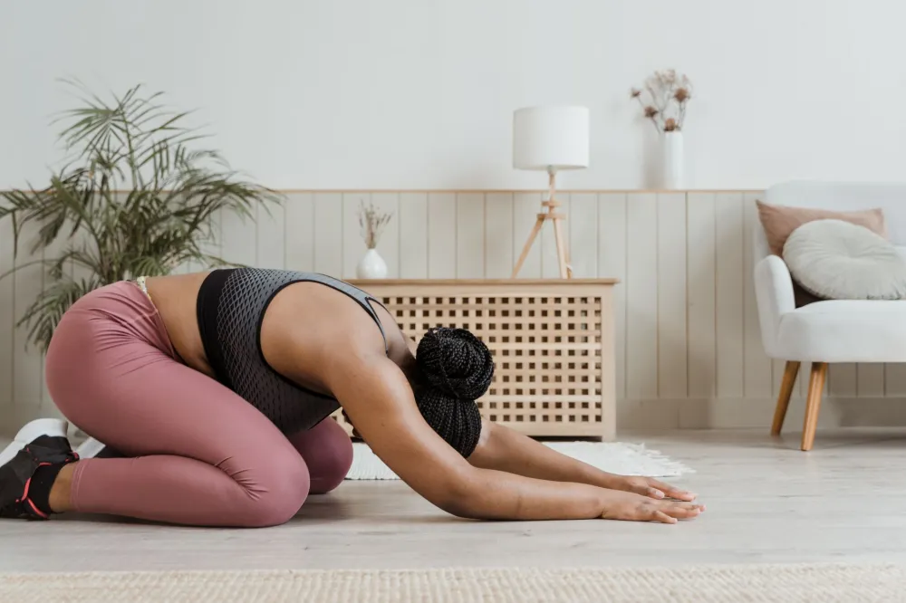 Yoga for Complete Beginners at Home: What Actually Works 3 Woman resting in child's pose on a yoga mat demonstrating a beginner resting position