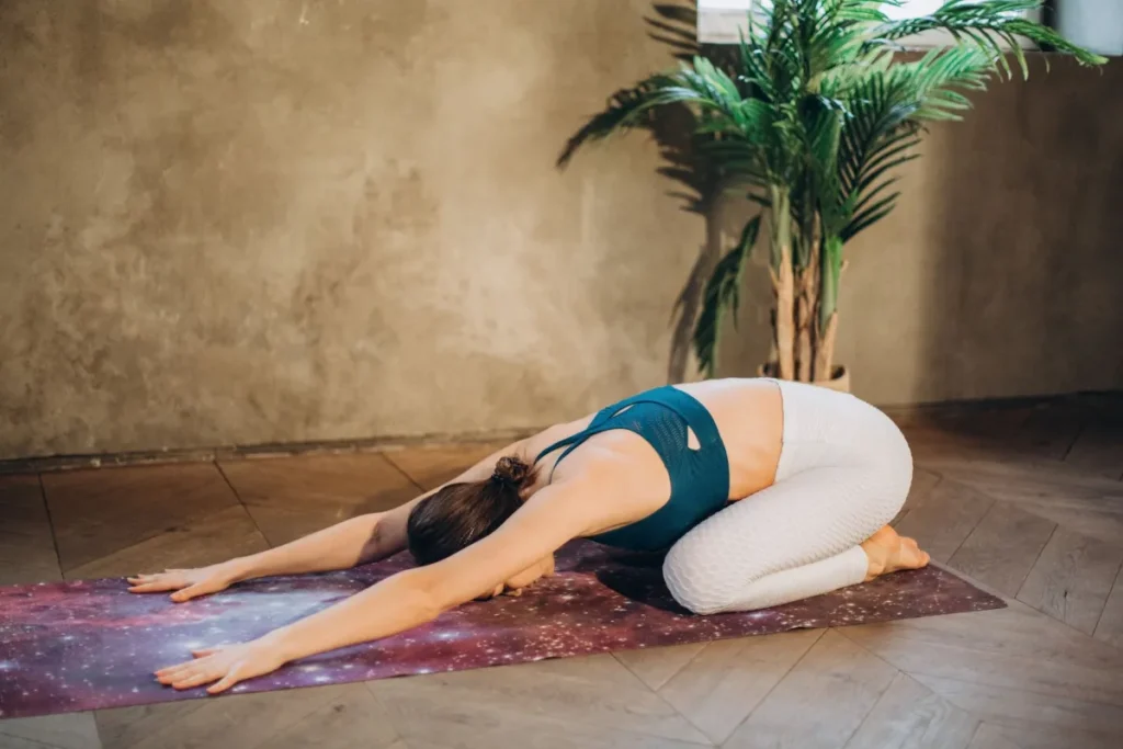 Woman practicing child's pose yoga stretch to ease lower back tension at home