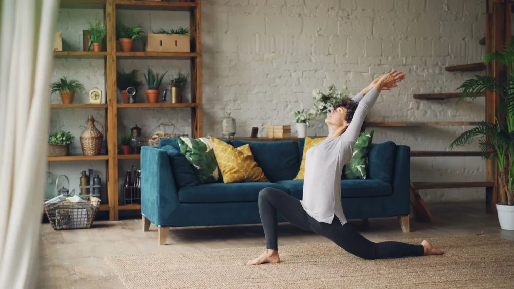 Woman doing gentle yoga stretches at home to relieve premenstrual breast pain