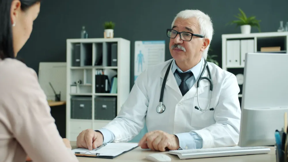 CoolSculpting Side Effects: Normal vs Rare Warning Signs 4 Doctor reviewing health history with a patient before a cryolipolysis consultation