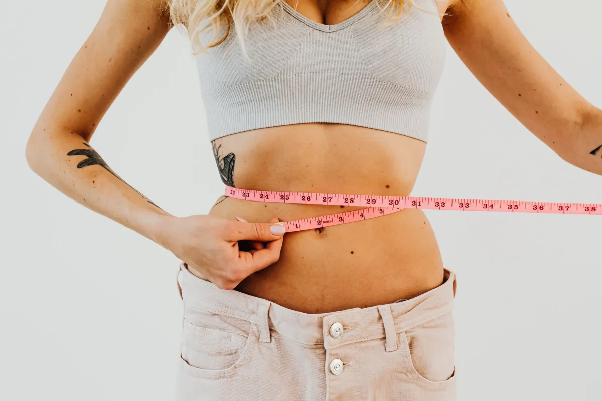 Woman measuring her waist while researching CoolSculpting side effects and recovery