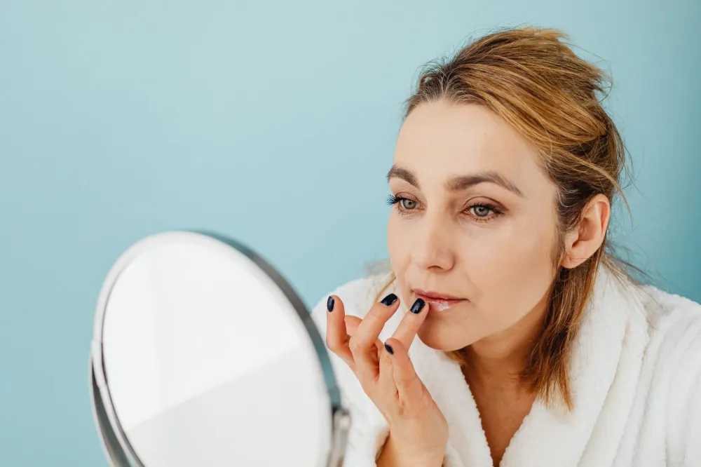 Young woman examining her lips closely in a bathroom mirror for skin bumps