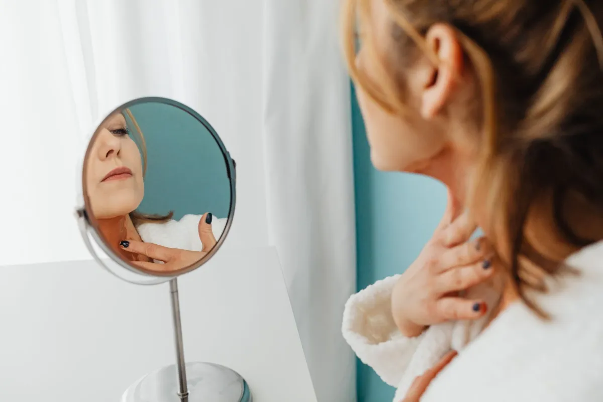 Young woman checking her neck in a bathroom mirror, wondering about hickey healing time