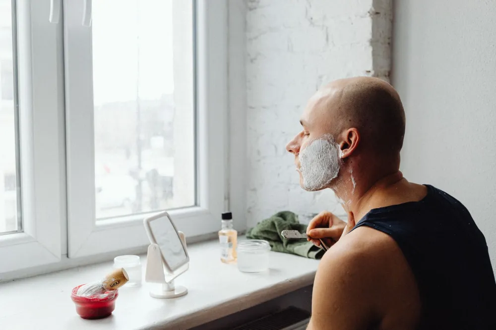 Person grooming with a razor, a common cause of ingrown hairs in the genital area