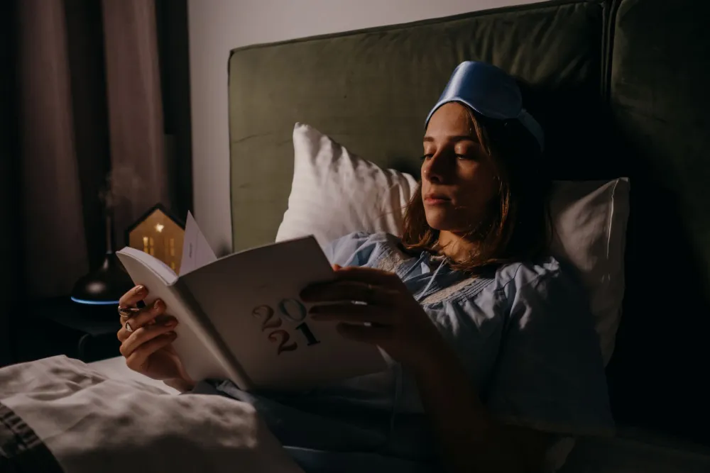 Woman writing in journal at bedside as part of a calming sleep routine