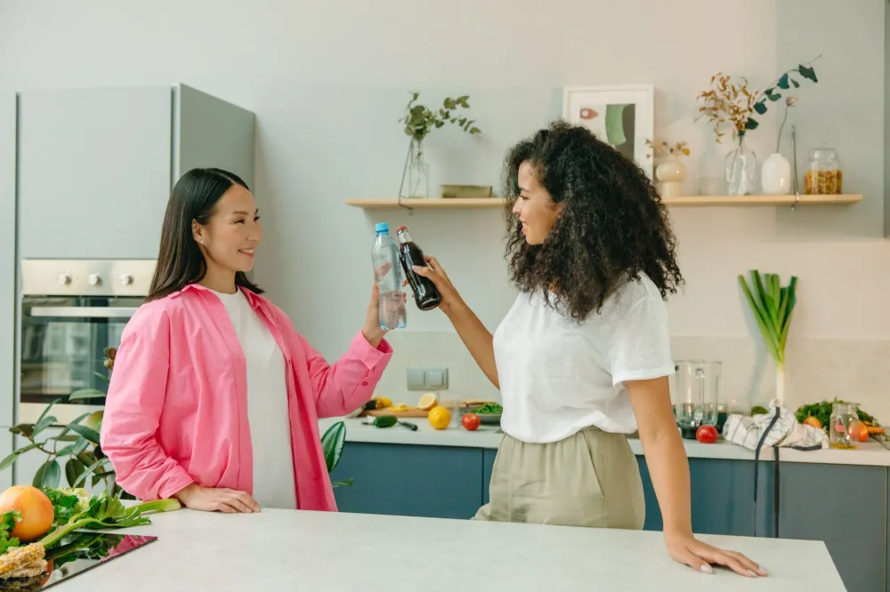 Woman drinking a glass of water in a bright kitchen during keto first week